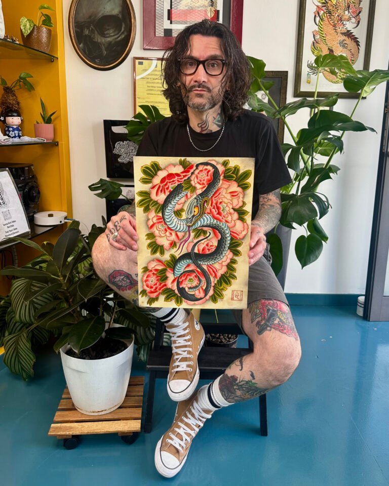 Beppe Shiro in studio con un dipinto di serpente e peonie