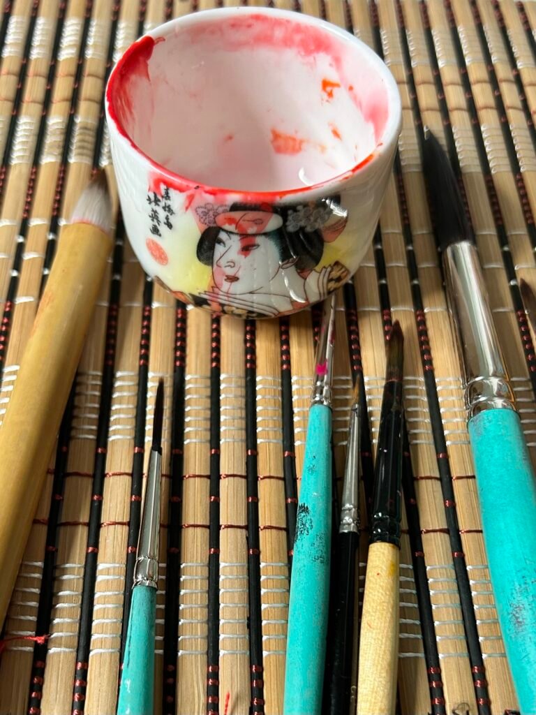 Brushes and sake cup on a bamboo mat
